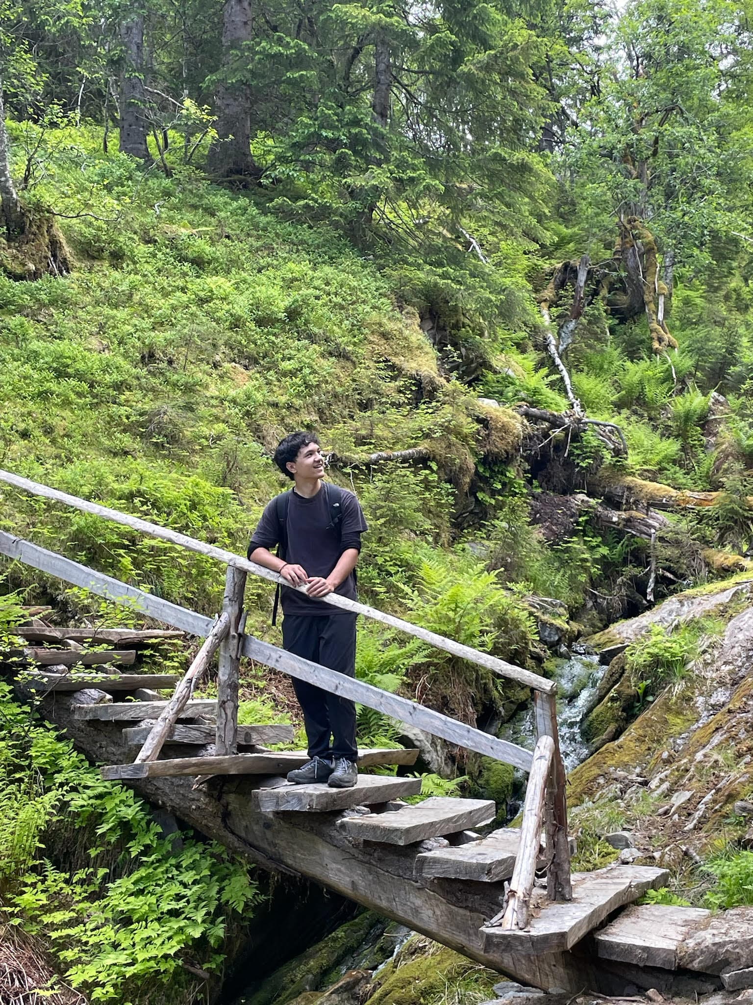 Tyler on a wooden bridge surrounded by trees